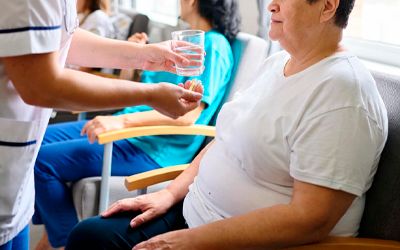 Медсестра подаёт стакан воды пожилой женщине